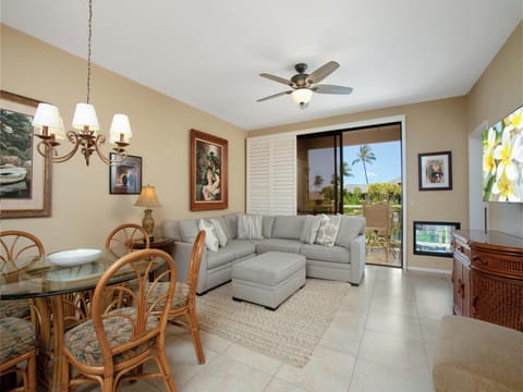 Step into your bright, island-inspired living space where tropical breezes drift through sliding doors. The open layout flows from dining to living area, offering comfort and easy access to your private outdoor space framed by swaying palms.