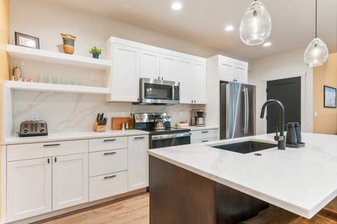 Sleek, well-equipped kitchen featuring stainless appliances and open shelving.