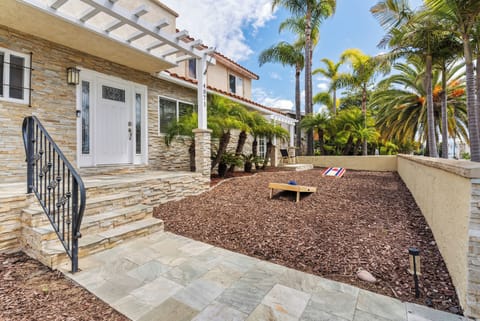 Welcoming entry with palm trees, stone steps, and outdoor seating.