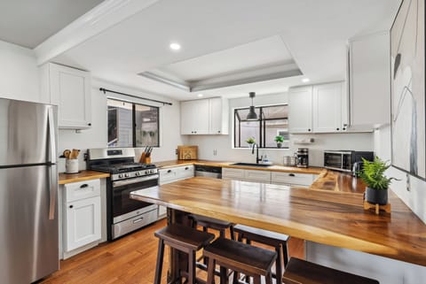 Sleek white kitchen with wood countertops. 