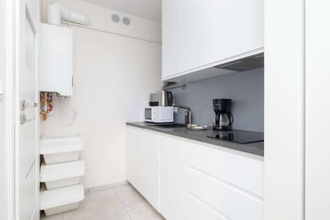 A compact kitchen with white cabinets and modern appliances. Functional design in a sleek style.