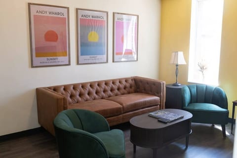 Cozy living room w/ tufted brown sofa, teal accent chair & bold sunset wall art for a colorful touch.