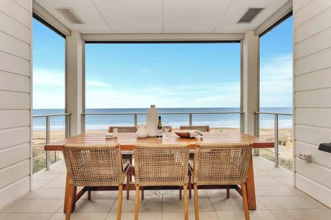 Dine alfresco on the private balcony, where a timber table and wicker chairs invite long meals with sweeping ocean views.