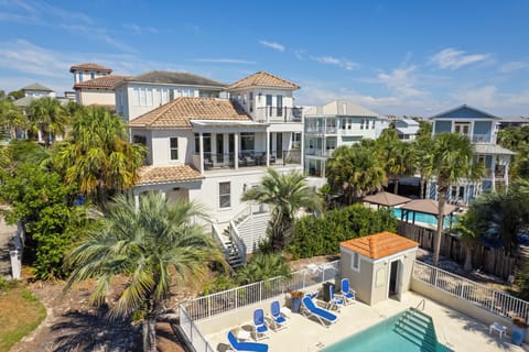 Aerial of communal pool and sun deck amid lush palms.