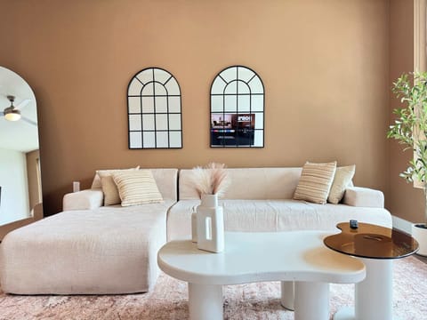 Spacious living room featuring a cozy L-shaped sofa, a full-size air mattress, and a 65" Smart TV with preloaded access to Netflix, Hulu, and Disney+, all set up for your enjoyment.