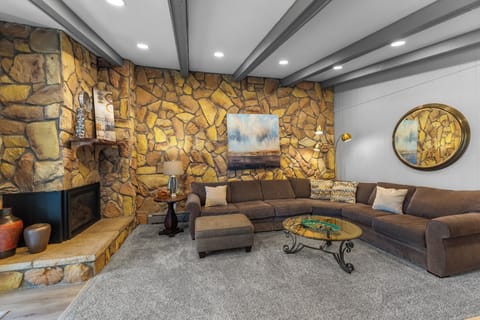 Curl up by the stone fireplace in this cozy living room, where rustic charm meets modern comfort for your perfect retreat.
