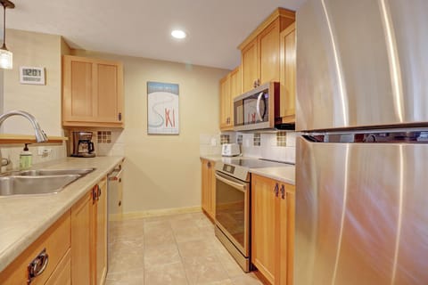 Well-equipped kitchen featuring stainless steel appliances, warm wood cabinetry, and ample counter space. Ideal for preparing hearty mountain meals after a day of skiing or hiking.