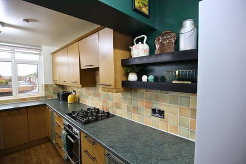 Kitchen hob area with open shelving and tiled splashback