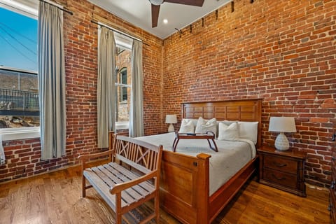 Bedroom 1 | King bed with warm wood furnishings, exposed brick walls, and natural light