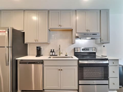 Modern kitchen with sleek stainless steel appliances and neatly arranged utensils, perfect for effortless cooking during your short-term rental stay.