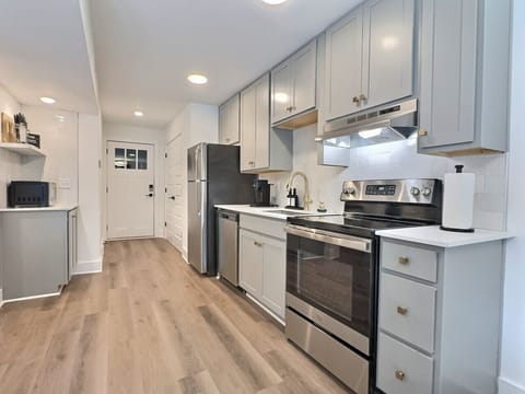 Modern kitchen with sleek stainless steel appliances and neatly arranged utensils, perfect for effortless cooking during your short-term rental stay.