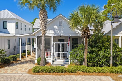 Charming coastal cottage with a screened porch and palm-lined entryway.