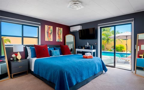 Spacious king bedroom in The Red Room, featuring bold red accents, modern artwork, and direct views of the pool through sliding glass doors.