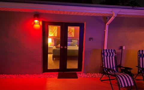 Private exterior entrance to The Red Room at night, featuring ambient lighting and a direct connection to the pool area.