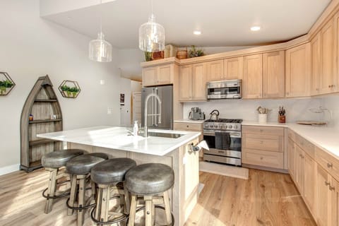 Mayflower Lakeside 1114-303: The fully equipped open kitchen has a central island with seating, light wood cabinets, and a modern tile backsplash with under-cabinet lighting.