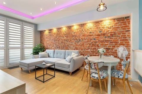 The brick wall and soft LED lighting create a warm, modern atmosphere in the living room, perfect for relaxing after a busy day.