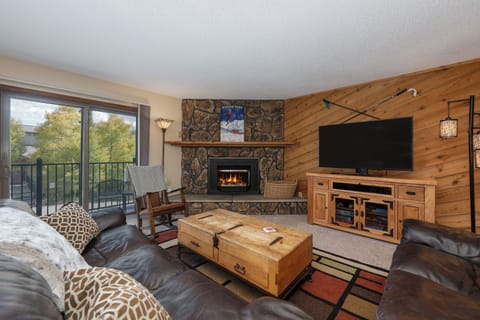 Cozy up by your crackling stone fireplace while enjoying mountain views from your private balcony in this warm, rustic living space.