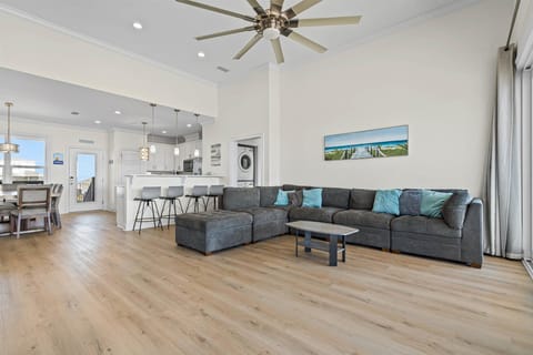 Sink into the plush sectional sofa and feel the coastal breeze from your ceiling fan in this airy open-concept living space.