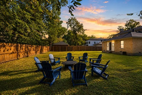 Spacious fenced backyard with fire pit seating under a sunset sky