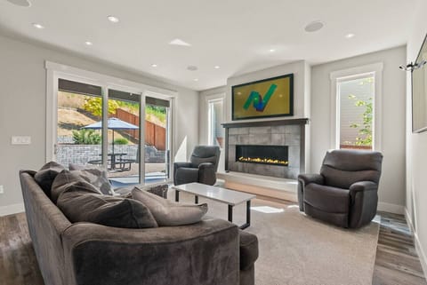 Cozy up in the modern living room with plush seating, a sleek gas fireplace, and sliding doors that open to the sunny patio for effortless indoor-outdoor relaxation.