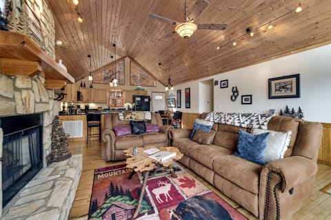 Open-concept great room with leather sofas, stone fireplace, and wall of windows overlooking the Smokies at Dream Weaver near the Nantahala River.