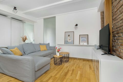 A sunlit lounge with a soft grey sofa, warm wooden floors, and minimalist decor creating a welcoming atmosphere.