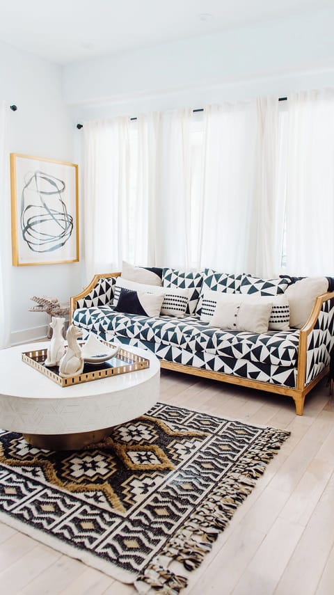 Chic living area with bold patterns, gold accents, and inviting natural light.