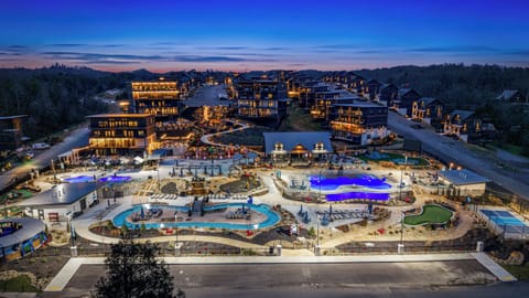 Night view of a modern resort featuring illuminated pools and surrounding accommodations.