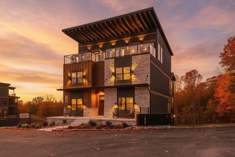 Modern three-story home with stone and metal exterior illuminated at sunset