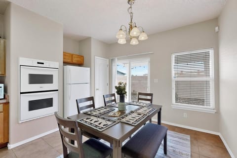 Dine in a modern space with a rustic table, comfy seats, and open kitchen.