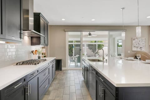 Contemporary kitchen featuring gas cooktop, island sink, and easy access to dining patio.