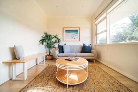 Relax into the sunlit lounge, where soft coastal tones, plush seating, and leafy street views create the perfect setting for slow mornings or quiet evenings in.