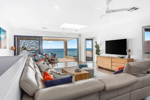 Settle into the sunlit living area where a generous corner lounge faces the TV and sliding doors open to sweeping ocean views beyond the balcony.