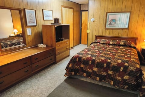 Unwind in a cozy queen bed with warm lamplight.
