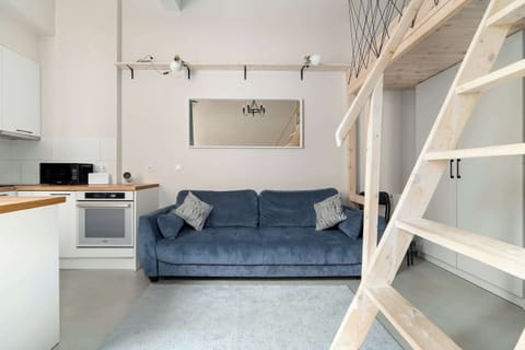 A bright living area with a blue sofa and mezzanine creates a space where you can relax after a day of exploring or working.