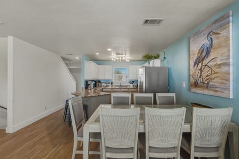 Dining table seats 7, with 4 barstools at counter and ample living room seating.