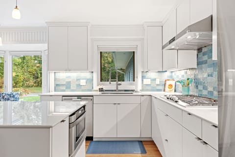 Your bright, modern kitchen features sleek white cabinets and a beautiful blue tile backsplash, perfect for preparing memorable meals during your stay.