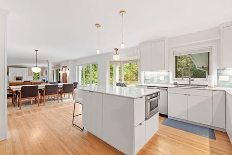 Your bright, modern kitchen flows seamlessly into the dining area, featuring sleek white cabinetry and a spacious island perfect for cooking together.