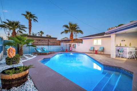 Private backyard with a pool, outdoor seating, fire pit, sun loungers, bar area, mini golf, covered patio, outdoor dining area, grill, and corn hole.