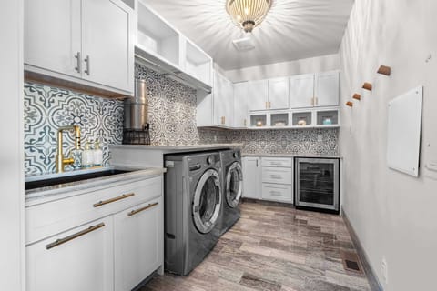 Even chores feel elevated here ... a designer laundry space featuring a patterned tile backsplash, gold accents, and extra touches like a wine fridge and water filter. Function meets luxury at every turn.