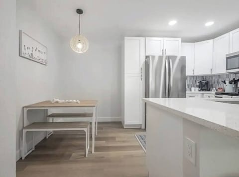 Charming dining nook with a modern wooden table and bench seating, illuminated by a stylish pendant light. Nestled beside the kitchen, it offers a cozy, contemporary space perfect for enjoying meals or morning coffee.
