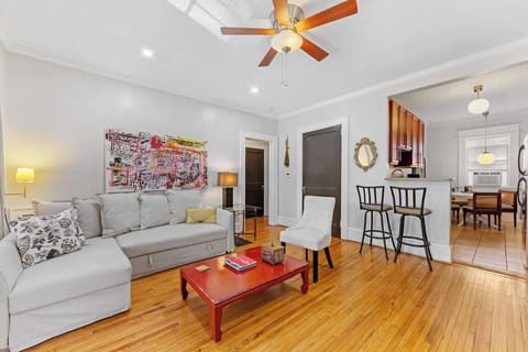 Open living area in Charlotte featuring hardwood floors, comfortable sofa with sleeper option, ceiling fan, and bright natural light. Flows into the dining space and kitchen, creating a welcoming layout for relaxing or entertaining.
