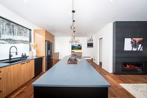 Prepare a meal in this luxuriously designed kitchen space.  The design of this space blends the relaxing living space next to a fire with what`s going on in the kitchen where the flat screen TV has a movie on.
