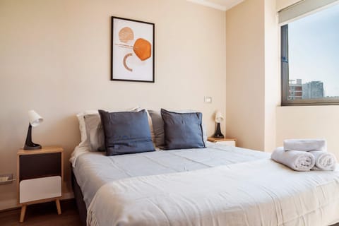 Cozy bedroom with modern decor and natural light, perfect for a relaxing stay.