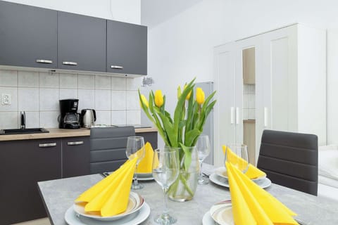 Close-up of the dining table elegantly decorated with fresh tulips, folded yellow napkins, and stylish tableware ready for a meal.