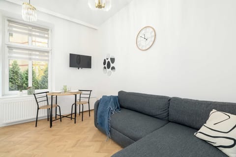 A compact living area combining a gray sofa, dining table, and wall-mounted TV. The interior feels calm and well-balanced.