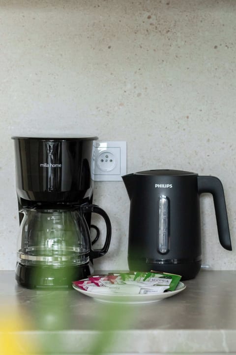 Countertop setup with a coffee maker, kettle, and cups, ready for everyday comfort and convenience.