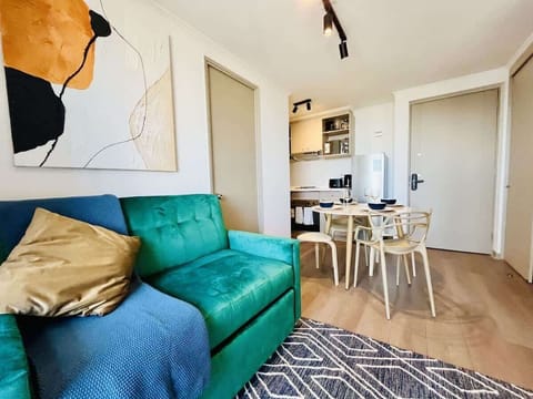 Bright living room w/ green sofa & cozy seating area flowing into the dining space