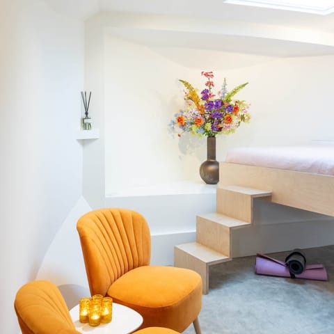 Our cosy living with comfortable bed, flowers, yoga mat and seating area - Houseboat Amsterdam BB