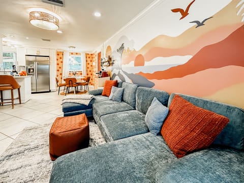 Living Room with Couch, 65" Roku TV, Indoor Electric LED Fire Place, Fandelier & Local Artist Mural